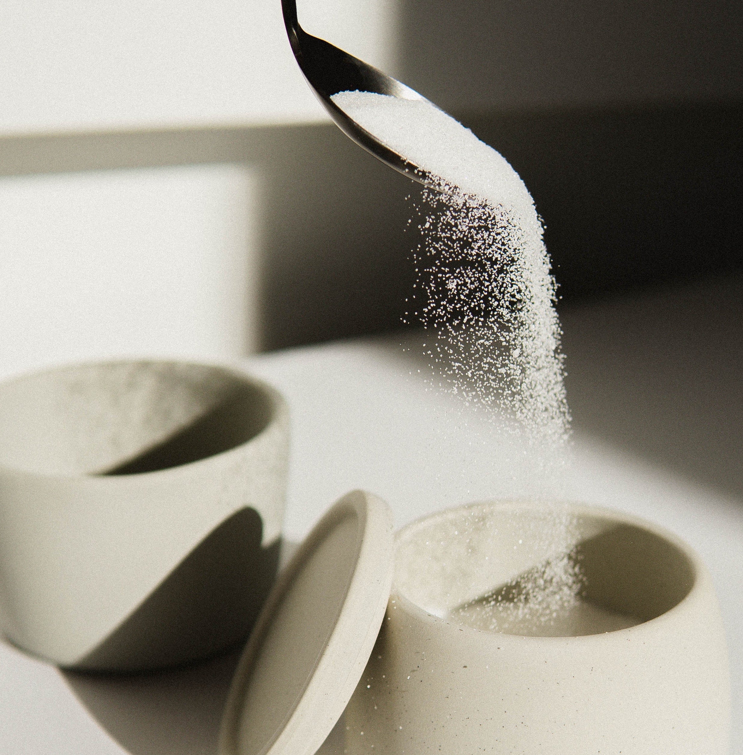 Cucchiaio con zucchero versato nel contenitore