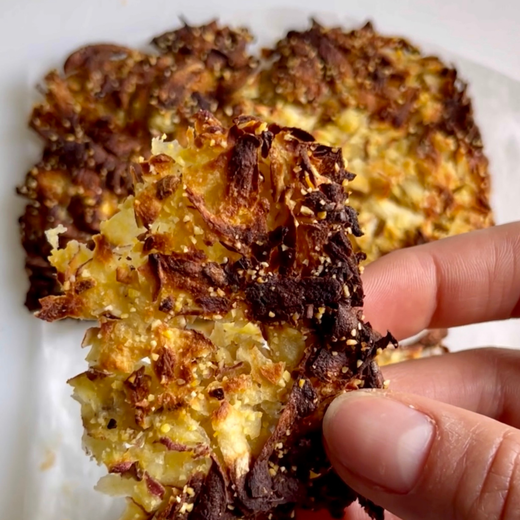 Mano che tiene un pezzo di patate hash brown croccanti