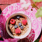 Colazione con mirtilli, lamponi e granola su un piatto fucsia