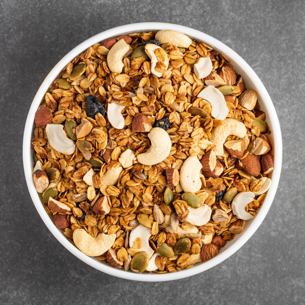 Ciotola con frutta secca e cereali su sfondo grigio