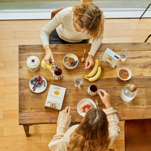 Visione dall'alto di due ragazze che fanno colazione con i prodotti Clemi's market come original granola, Chocolate Lover Granola